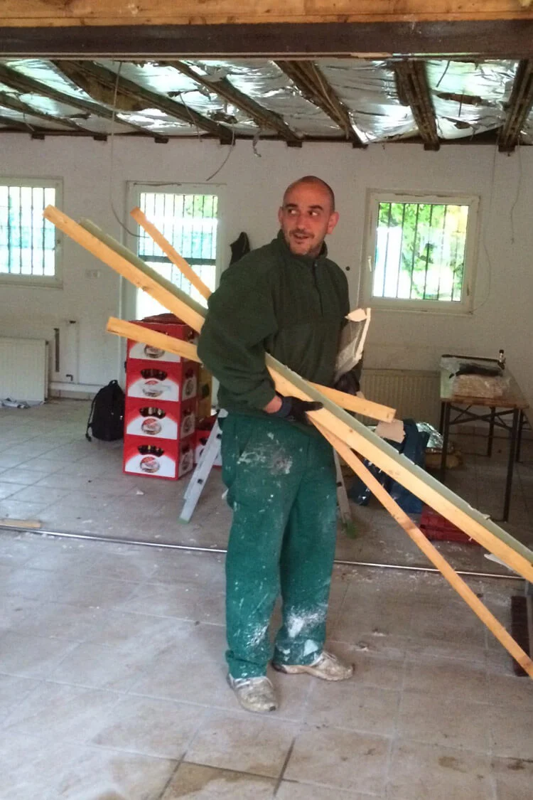 Ausführender Bauherr des Projekts: Joschi Große trägt einige Dachlatten nach draußen Ausführender Bauherr des Projekts: Joschi Große trägt einige Dachlatten nach draußen