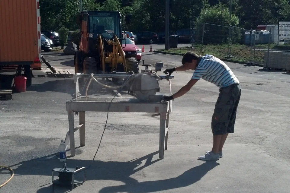 Viktor Adam schneidet die Pflastersteine an der Maschine zurecht